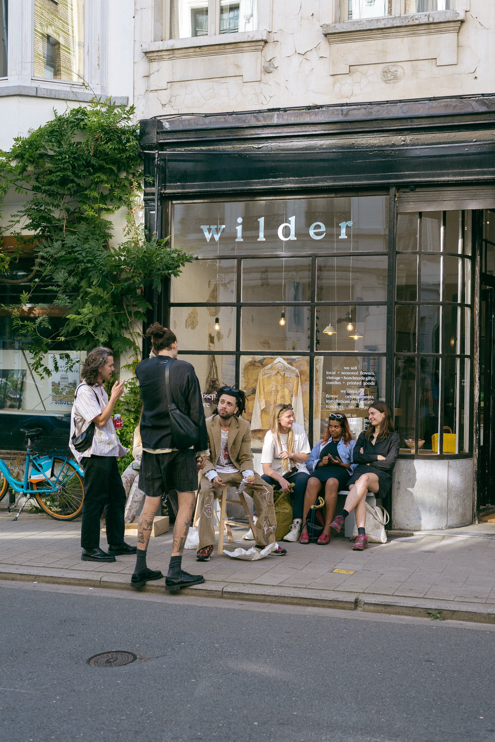 A group of people sitting in front of the former Wilder store at Provinciestraat 28